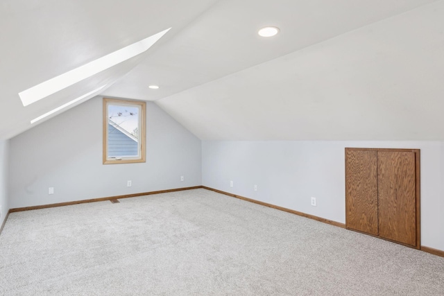 additional living space with lofted ceiling with skylight and light colored carpet