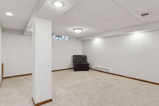 basement with light carpet, a baseboard radiator, and a paneled ceiling