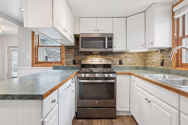 kitchen with sink, backsplash, stainless steel appliances, dark hardwood / wood-style floors, and white cabinets