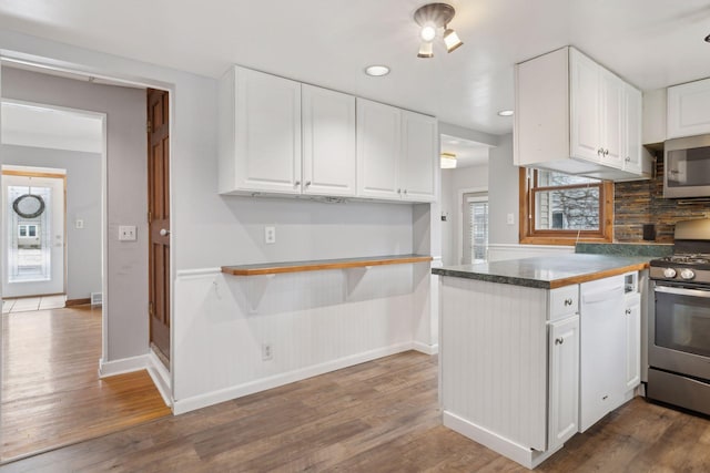 kitchen with dark wood-type flooring, stainless steel appliances, and white cabinets