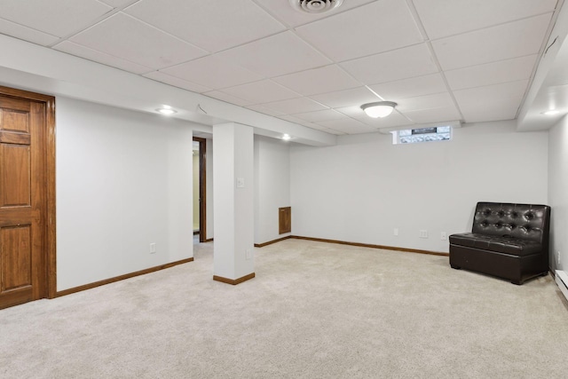 basement featuring a paneled ceiling and light colored carpet