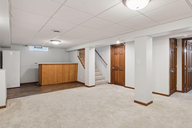 basement featuring light colored carpet and a drop ceiling