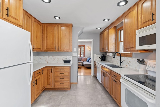 kitchen with backsplash, white appliances, light countertops, and a sink