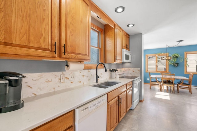 kitchen featuring a sink, tasteful backsplash, white appliances, light countertops, and baseboards