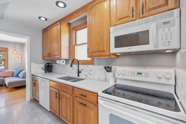 kitchen featuring light countertops, light tile patterned floors, decorative backsplash, white appliances, and a sink