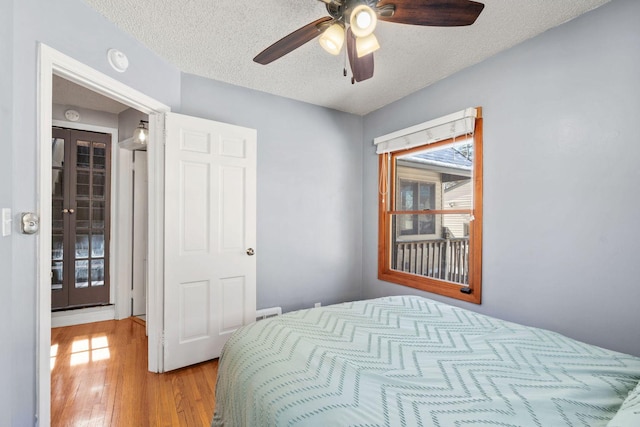 bedroom with french doors, a textured ceiling, ceiling fan, and wood finished floors