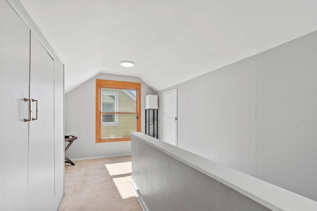 hallway with baseboards, light carpet, lofted ceiling, and an upstairs landing