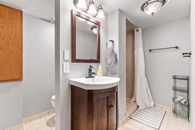 bathroom featuring vanity, tile patterned floors, toilet, and a tile shower