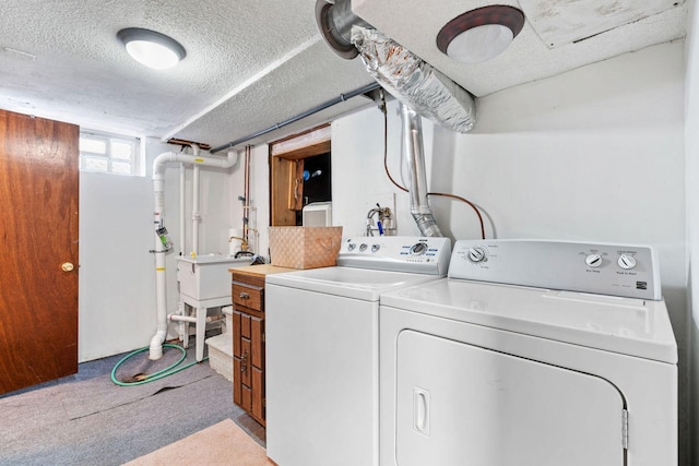 laundry area featuring washer and dryer, light colored carpet, cabinet space, and a textured ceiling