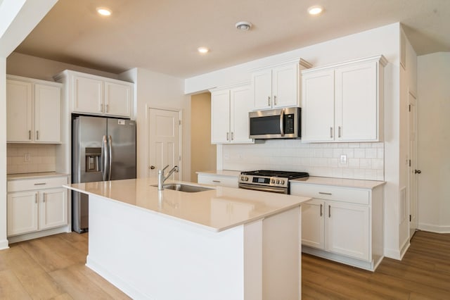 kitchen featuring white cabinetry, sink, stainless steel appliances, and a center island with sink