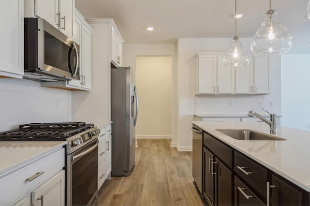 kitchen featuring pendant lighting, stainless steel appliances, sink, and white cabinets