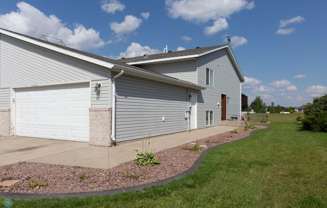 view of side of property featuring a garage and a lawn