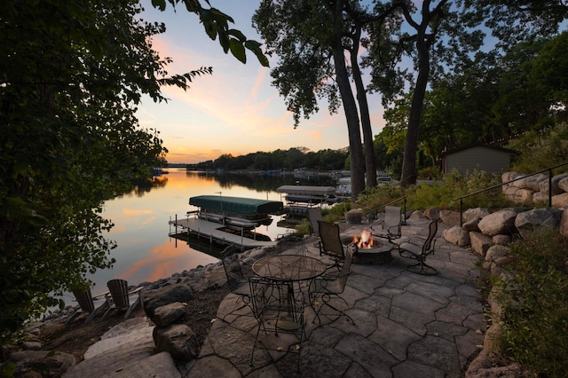 view of patio with a fire pit, a water view, and a floating dock