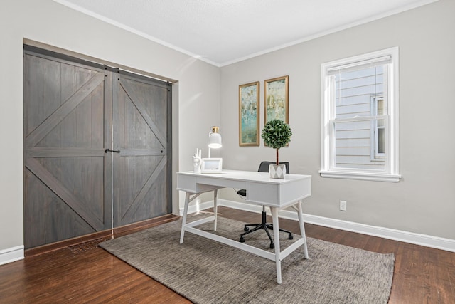 home office featuring dark wood-type flooring, ornamental molding, and a barn door