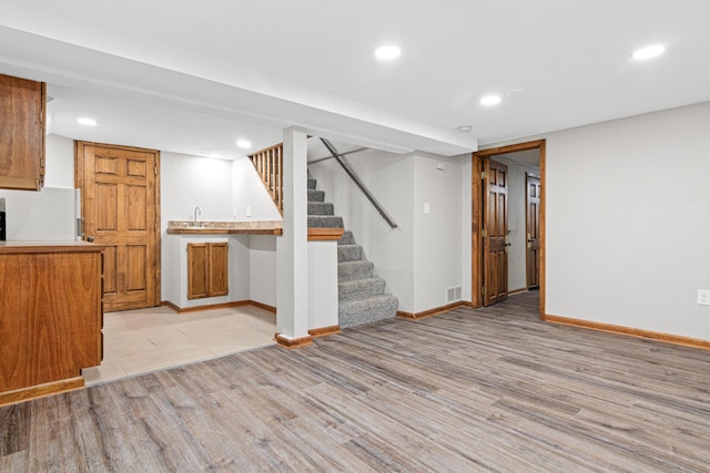 kitchen with sink, light hardwood / wood-style flooring, kitchen peninsula, and white fridge