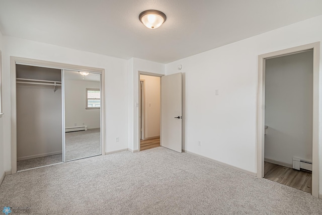 unfurnished bedroom with light carpet, baseboard heating, and a closet