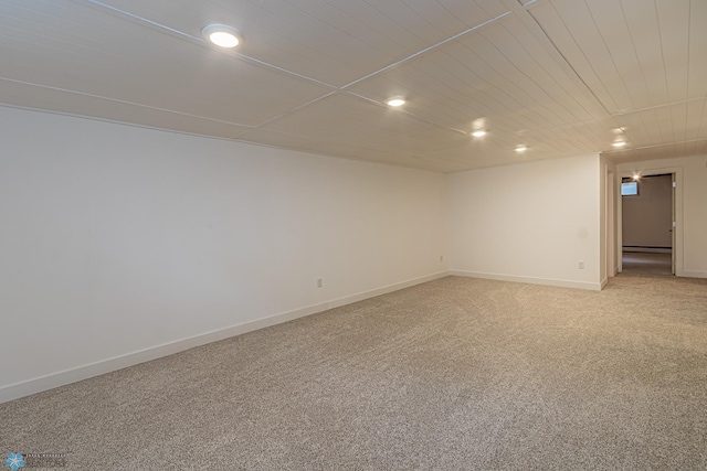 carpeted empty room with baseboard heating and wood ceiling