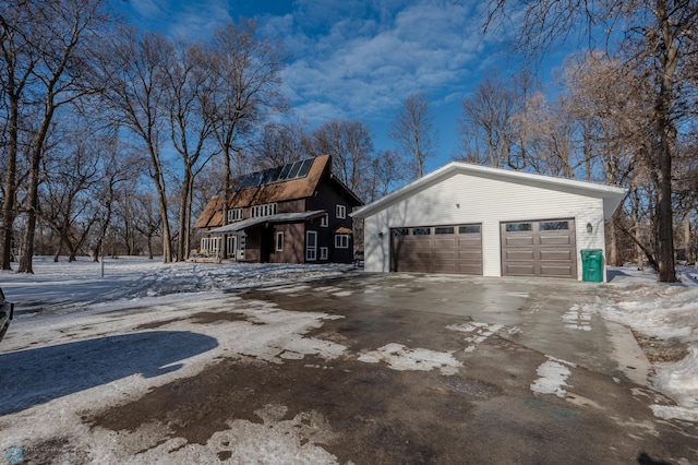 snow covered property with an outbuilding and a garage