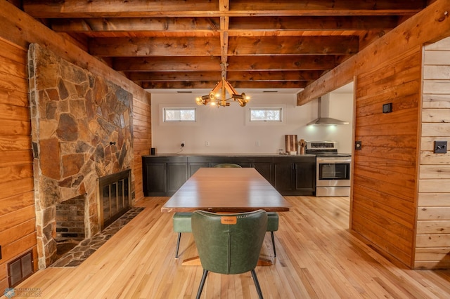 dining room with light wood-type flooring, a fireplace, and beam ceiling