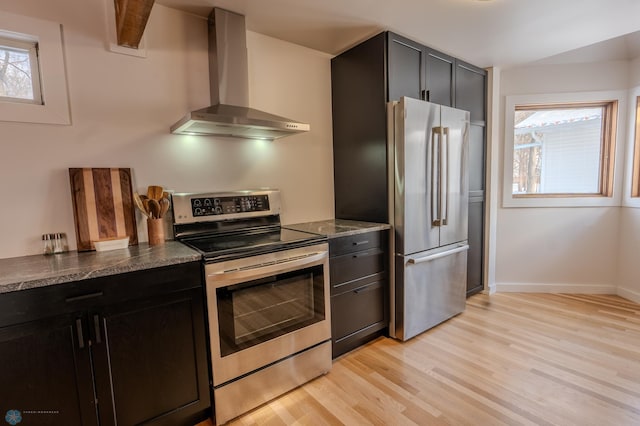 kitchen featuring a healthy amount of sunlight, stainless steel appliances, wall chimney exhaust hood, and light wood-type flooring