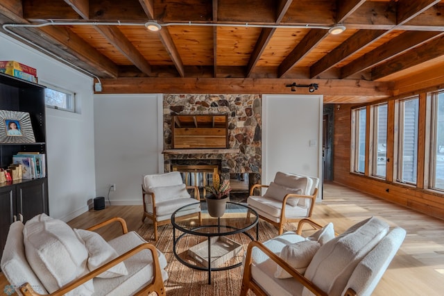 living room featuring light hardwood / wood-style flooring, beam ceiling, a fireplace, and wooden ceiling