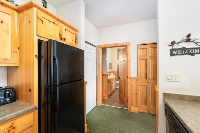 kitchen featuring light brown cabinets, dark carpet, and black appliances