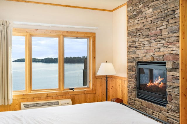 unfurnished bedroom with a water view, ornamental molding, a stone fireplace, and multiple windows