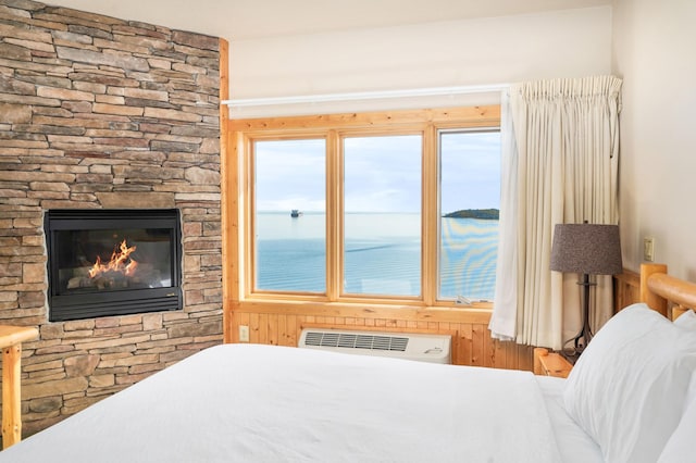 bedroom featuring a water view, radiator heating unit, and a stone fireplace