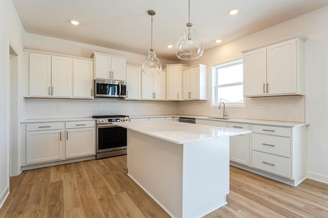 kitchen featuring white cabinetry, appliances with stainless steel finishes, sink, and decorative light fixtures