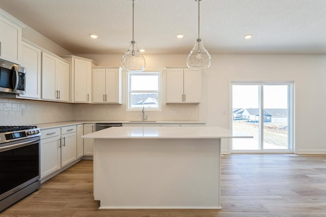 kitchen featuring pendant lighting, white cabinetry, a center island, and appliances with stainless steel finishes