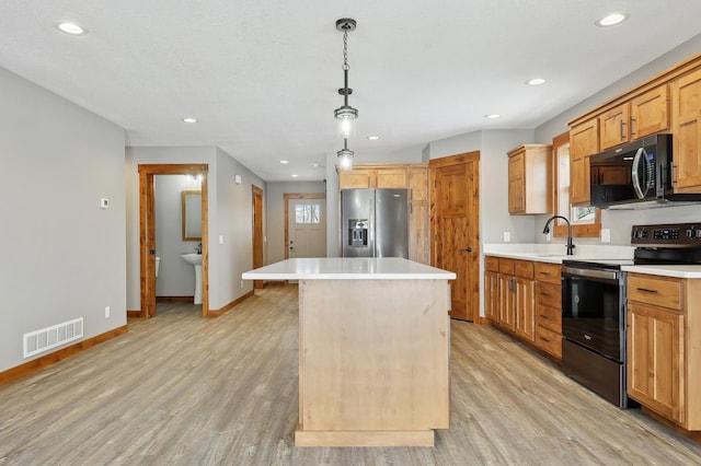 kitchen featuring stainless steel appliances, a kitchen island, pendant lighting, and light wood-type flooring