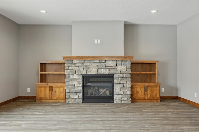 unfurnished living room with a fireplace, a textured ceiling, and light wood-type flooring