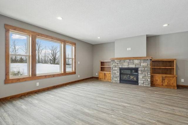 unfurnished living room with a fireplace, a textured ceiling, and light wood-type flooring