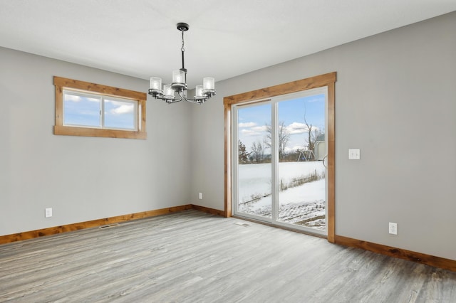 unfurnished room featuring wood-type flooring and an inviting chandelier