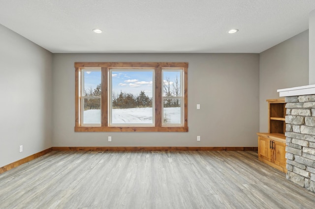 unfurnished living room with a textured ceiling and light hardwood / wood-style flooring