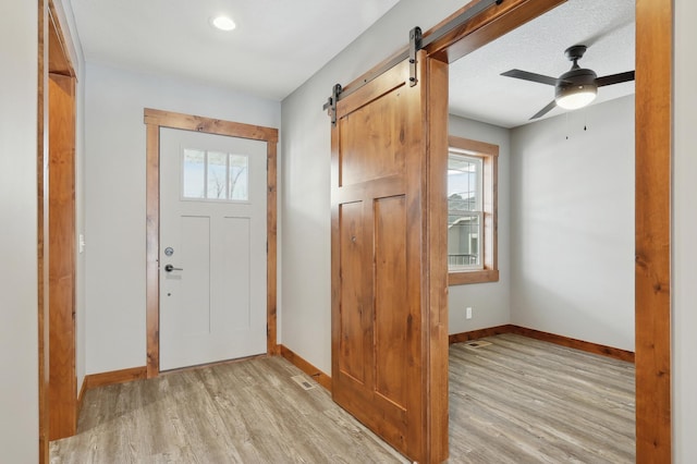 entrance foyer with light hardwood / wood-style floors, a barn door, and a healthy amount of sunlight