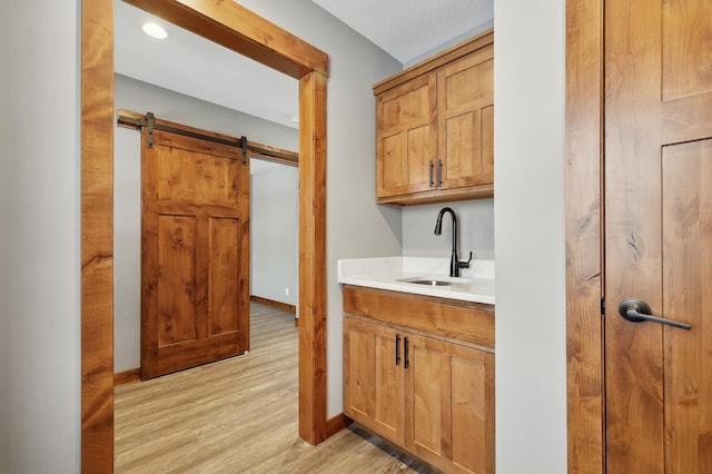 bar with sink, a barn door, and light wood-type flooring