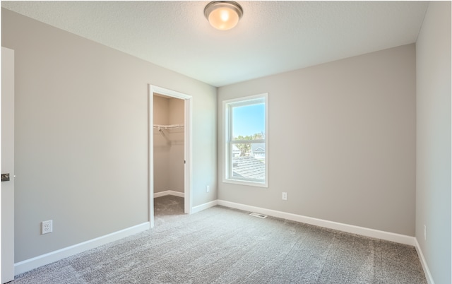 unfurnished bedroom featuring a spacious closet, light carpet, and a closet