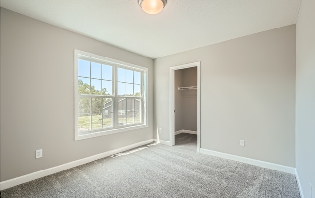 unfurnished bedroom featuring carpet floors, a walk in closet, and a closet