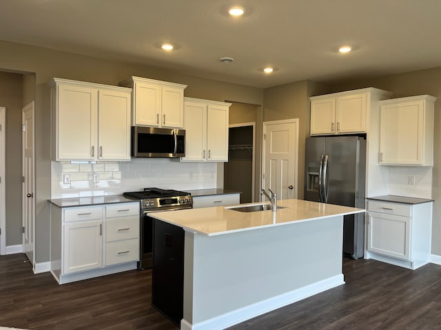 kitchen featuring sink, appliances with stainless steel finishes, white cabinetry, tasteful backsplash, and a center island with sink