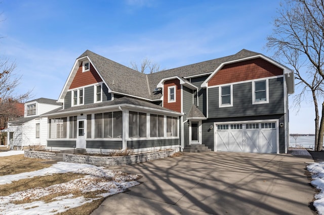 view of front of home featuring driveway, roof with shingles, an attached garage, a sunroom, and entry steps