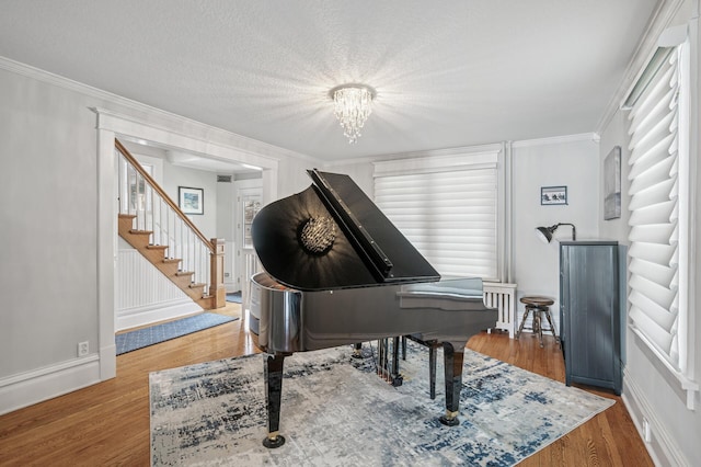 living area with crown molding, stairway, and wood finished floors