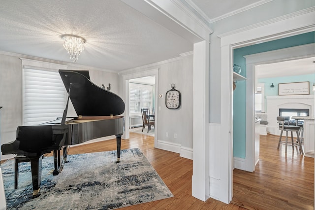 sitting room with a chandelier, ornamental molding, a fireplace, wood finished floors, and a textured ceiling