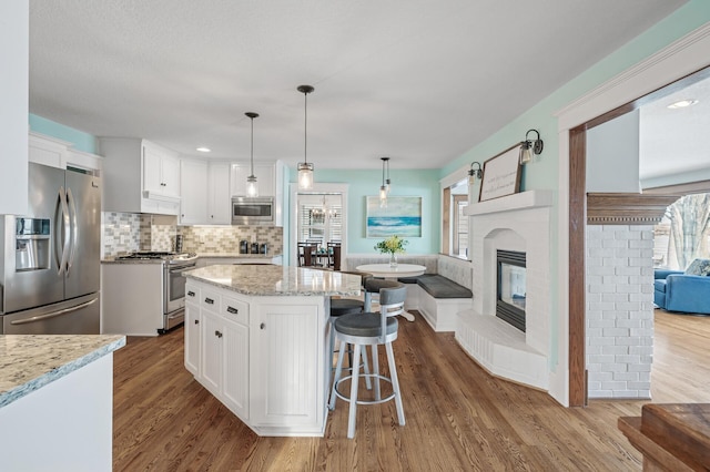 kitchen featuring open floor plan, appliances with stainless steel finishes, white cabinetry, and dark wood-type flooring