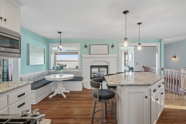 kitchen featuring stainless steel microwave, white cabinets, dark wood-style flooring, and breakfast area