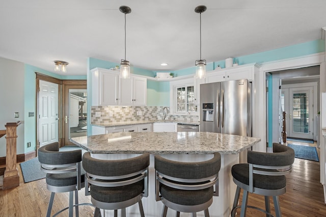 kitchen featuring tasteful backsplash, appliances with stainless steel finishes, white cabinetry, and wood finished floors