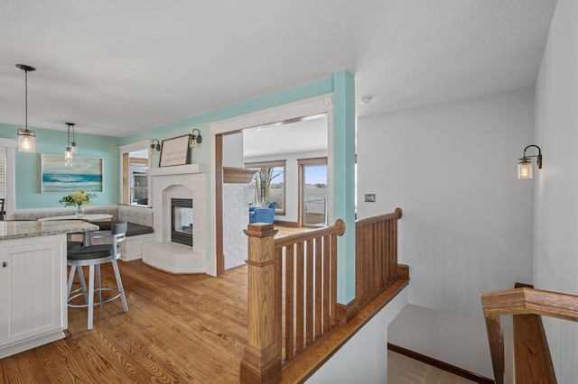 hall featuring light wood finished floors, an upstairs landing, and baseboards