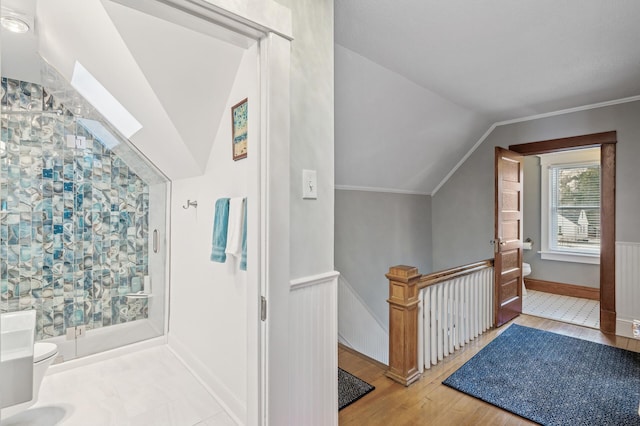 additional living space featuring hardwood / wood-style flooring, a wainscoted wall, and lofted ceiling