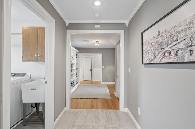 hall with baseboards, a textured ceiling, ornamental molding, and washer / clothes dryer