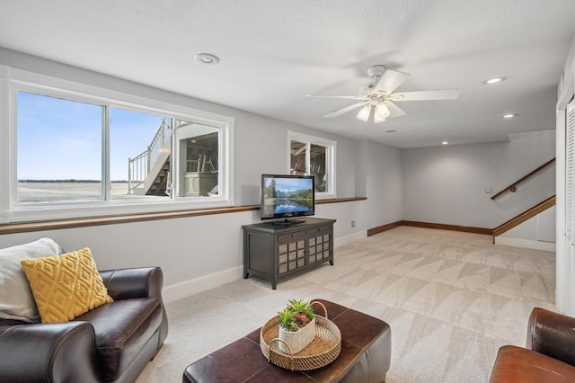 living area featuring stairway, baseboards, recessed lighting, ceiling fan, and light colored carpet